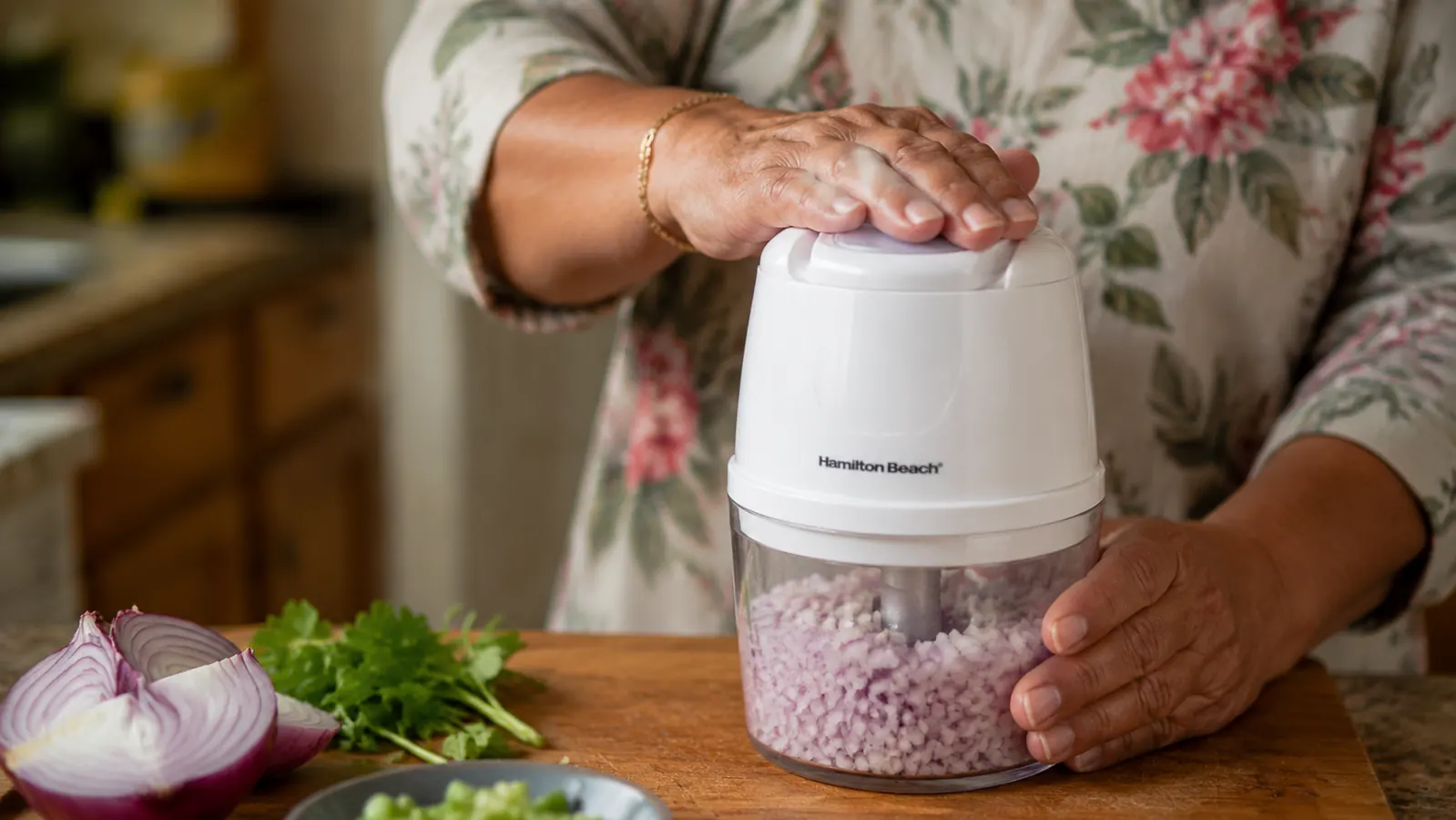 Hand pressing the top lid of the Hamilton Beach food chopper with vegetables inside