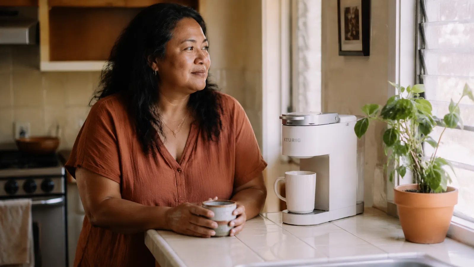 Keurig K-Mini coffee maker on a small kitchen counter next to a mug in warm morning light