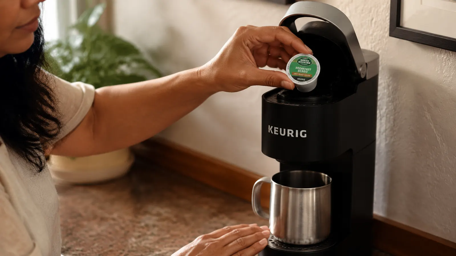 Close-up of a hand placing a K-Cup pod into the Keurig K-Mini coffee maker