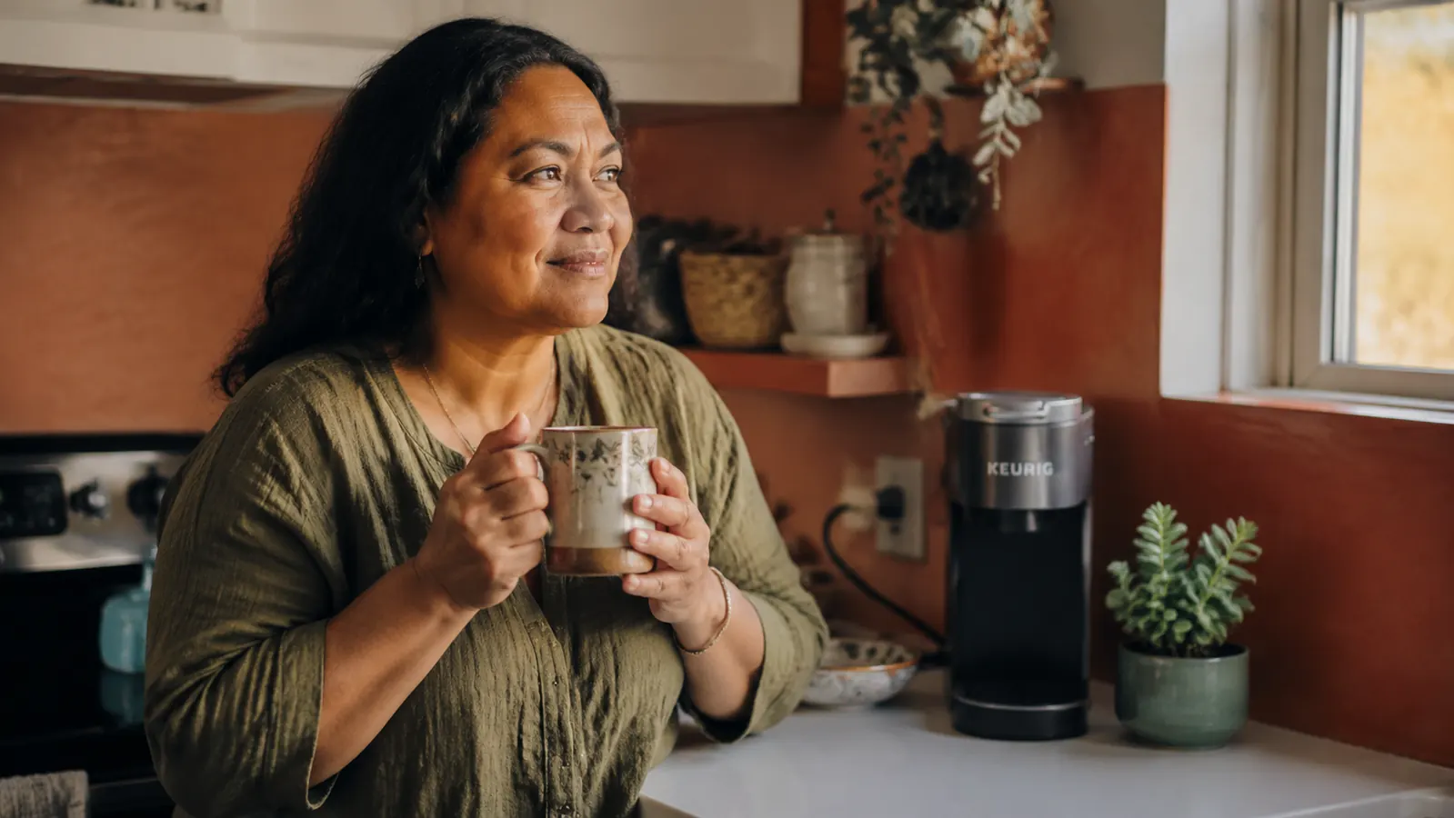 The Keurig K-Mini coffee maker on a countertop next to a window with a golf ball resting nearby as a lighthearted detail
