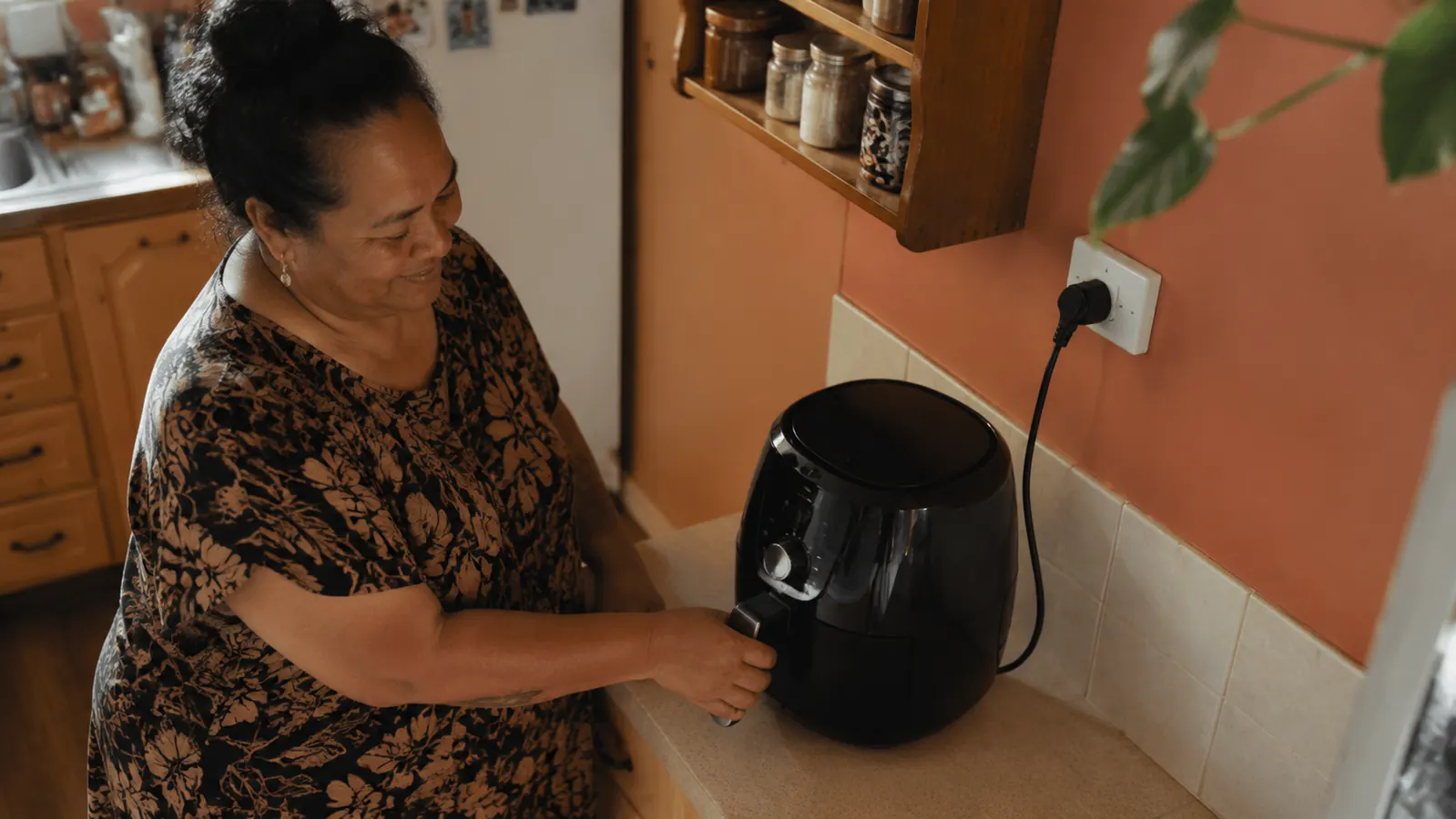 Small kitchen counter showing the Ninja air fryer with its power cord running along the baseboard to a nearby outlet